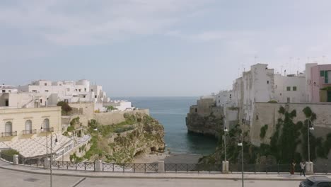 Aerial-footage-flying-over-a-bridge-and-over-Lama-Monachile-towards-the-sea-in-Polignano-a-Mare,-Italy