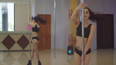 Sexy-latina-walking-around-the-pole-at-a-pole-dancing-studio