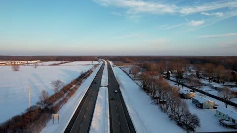 Aerial-view-of-cars-driving-on-a-snowy-highway-on-a-background-of-blue-sky