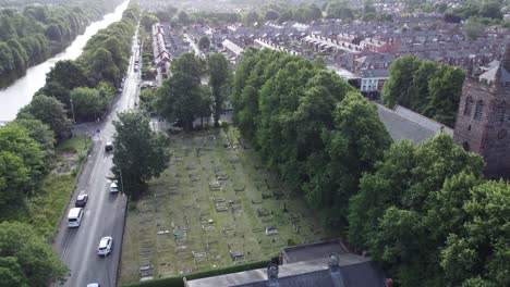 Scenic-aerial-view-above-quaint-countryside-village-church-cemetery-and-canal-waterway-orbit-left-shot