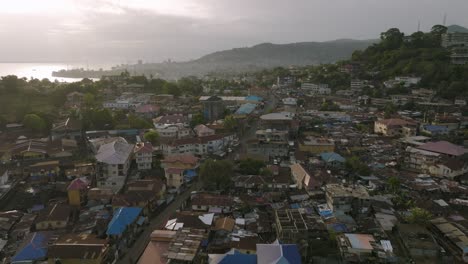 Fast-aerial-flyover-of-downtown-Freetown,-Sierra-Leone-during-the-sunrise-with-morning-traffic