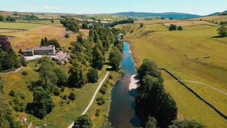 Ariel-Drone-footage-of-peaceful-river-surrounded-by-farmland-in-the-Yorkshire-Dales-National-Park,-UK