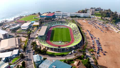 Aerial-of-a-Soccer-League-game-being-played-in-Santiago-Wanderers-Stadium-in-Valparaíso,-sea-in-background,-Chile