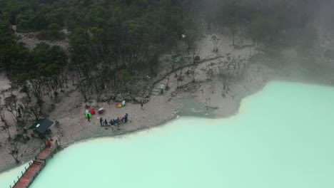 tourists-on-edge-of-extreme-sulfur-lake-Kawah-Putih-in-Bandung-Indonesia,-aerial