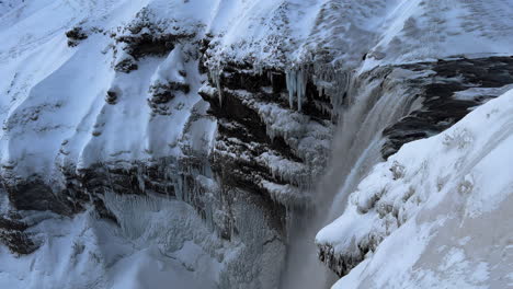 Cascada-De-Seljalandsfoss-En-Invierno-Islandia,-Vista-En-Cámara-Lenta-De-La-Cascada-De-Las-Cataratas-Y-Flujo-De-Agua-Desde-Un-Alto-Acantilado-Rocoso-Nevado-Congelado,-Famoso-Sitio-De-Destino-Turístico
