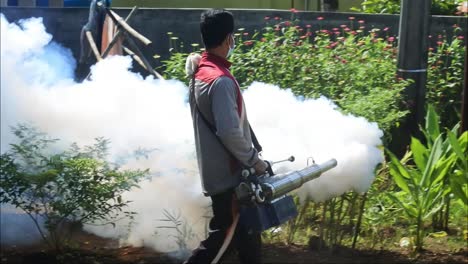 Professional-person-with-equipment-using-a-fogging-machine-with-insecticide-to-Eliminate-mosquitos-as-aedes-aegypti-in-an-outdoors-in-Sukabumi,-West-Java,-Indonesia-on-May-8,-2022