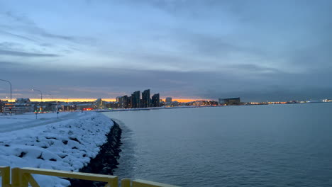 Weite-Aufnahme-Der-Stadt-Reykjavik-Und-Des-Atlantischen-Ozeans-Im-Winter-Nach-Sonnenuntergangszeit-Auf-Island