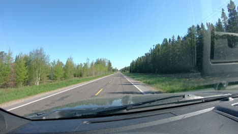 POV-while-driving-on-a-narrow-county-road-past-golf-course-in-rural-northern-Minnesota-in-early-spring-on-a-bright-day