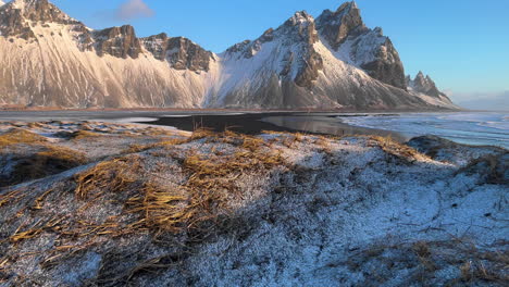 Vestrahorn-Mountain-En-Islandia,-Dolly-Forward-Wilderness-Paisaje-Invernal-De-Tierras-Nevadas-De-La-Costa,-Montaña-Rocosa-Y-Costa-En-Segundo-Plano.