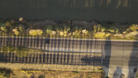 Aerial-top-down-shot-of-car-driving-on-coastal-boulevard-road-beside-river-in-Buenos-Aires-during-sunny-day