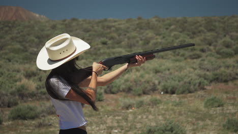 Pretty-caucasian-girl-skeet-shooting-in-the-desert,-fires-pump-action-shotgun-with-heavy-recoil