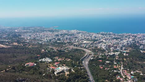 Fliegen-über-Eine-Autobahn-Mit-Blick-über-Die-Weitläufige-Stadt-In-Richtung-Mittelmeer