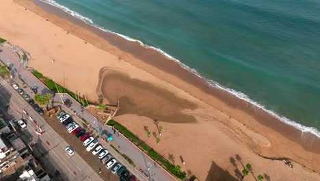 Aerial-dolly-in-of-Recaña-sand-beach-and-turquoise-sea-near-hillside-with-luxury-apartments,-Chile