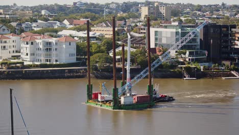 A-flat-deck-barge-transporting-a-small-crawler-crane-up-a-river
