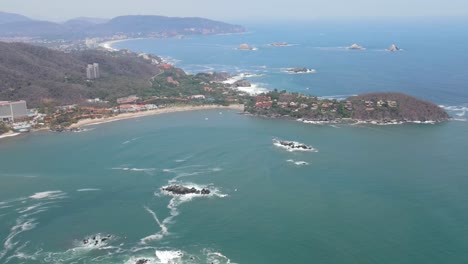 Drone-flying-over-the-skies-of-Ixtapa-beach-called-Isla-Grande-located-in-the-state-of-Guerrero,-Mexico-during-a-sunny-day-from-a-long-distance
