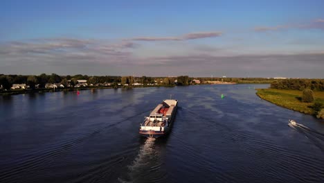Aerial-Stern-View-Of-FPS-Waal-Inland-Cargo-Vessel-Along-Oude-Maas-With-During-Golden-Hour