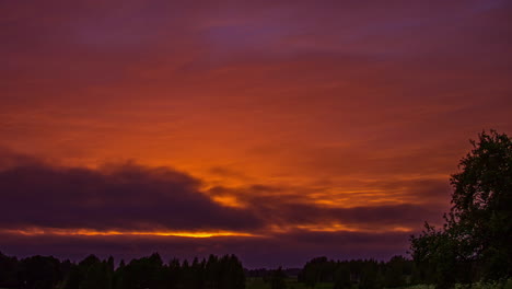 Low-angle-shot-over-red-sunset-sky-with-dark-cloud-movement-in-timelapse