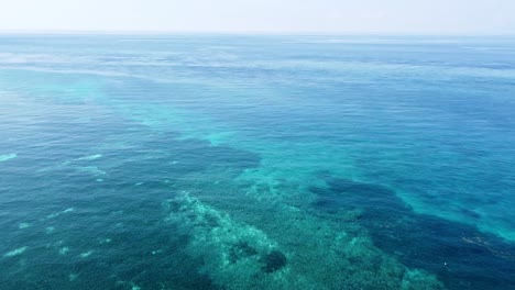 Umgekehrter-Drohnenflug-über-Ein-Atemberaubendes-Korallendreieck-Und-Kristallklares-Türkisfarbenes-Meerwasser-Auf-Einer-Abgelegenen-Tropischen-Insel-In-Südostasien