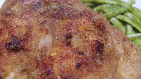 Super-close-up-of-fried-breaded-chicken-on-green-spaghetti