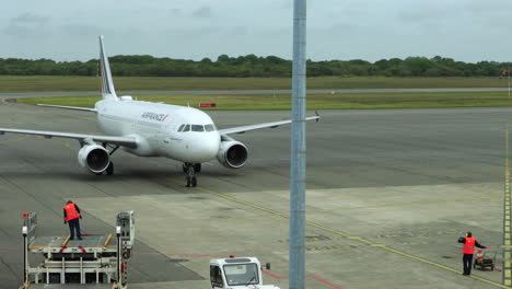 El-Personal-De-Tierra-Guía-El-Jet-De-Air-France-A-La-Puerta-De-Estacionamiento-En-El-Aeropuerto-De-Brest,-Francia