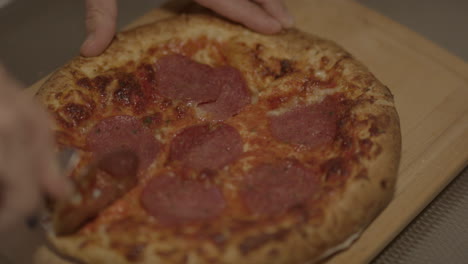 Peperoni-Pizza-Auf-Einem-Holzbrett,-Die-Mit-Einem-Pizzaschneider-Geschnitten-Wird---240-Fps