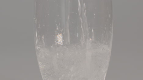tilt-up-of-Sparkling-water-being-poured-into-glass-against-a-white-studio-background
