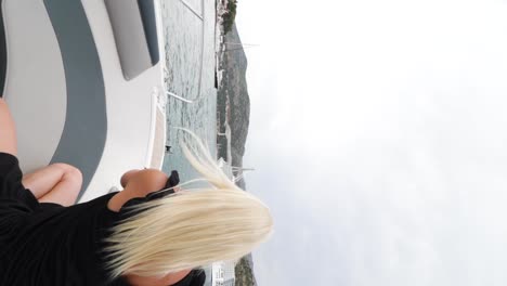 A-young,-attractive-Caucasian-woman-dressed-in-a-black-dress-is-sitting-and-taking-a-photo-out-into-the-Adriatic-Sea-from-a-speedboat-in-Croatia