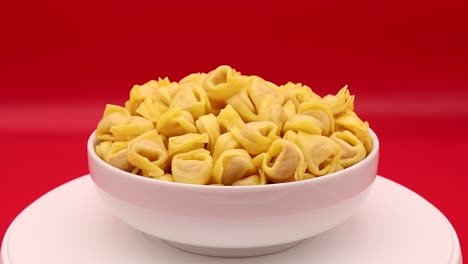 Raw-Tortellini-rotating-on-a-red-background
