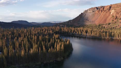 Aerial-descending-shot-of-a-quiet-alpine-lake-in-the-mountains-at-sunset