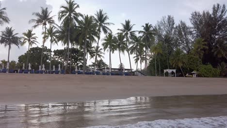 slowmotion-POV-of-the-white-sand-beach-with-wave-in-sea-and-coconut-trees-on-beach-in-slow-motion