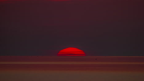 Static-shot-of-sun-rising-at-dawn-over-the-Pacific-ocean-along-the-colorful-red-sky-over-the-sea-waves-in-morning-time