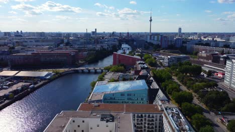 Spree,-TV-tower,-S-Bahn-station-train-arrives-Smooth-aerial-view-flight-pan-from-left-to-right-drone-footage-of-Berlin-Friedrichshain-sunny-Summer-day-2022-Cinematic-view-from-above-by-Philipp-Marnitz