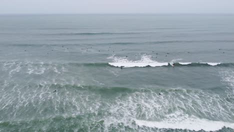 Drohnenvideo-Von-Surfern-Auf-Einer-Welle,-Während-Viele-Andere-Surfer-Auf-Ihre-Wellen-Warten