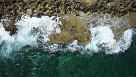 Aerial-top-down-trucking-shot-of-the-ocean-waves-crashing-on-the-volcanic-rocks