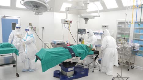 Asian-Medical-Staff-Wear-PPE-Walk-Into-Operating-Room-With-Patient-On-Operating-Table