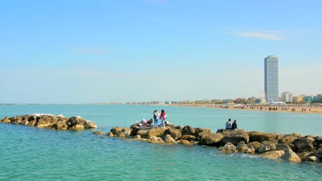Tourists-Enjoying-Daytime-Tour-In-Rocky-Path-By-The-Sea-In-Cesenatico,-Italy---wide-shot
