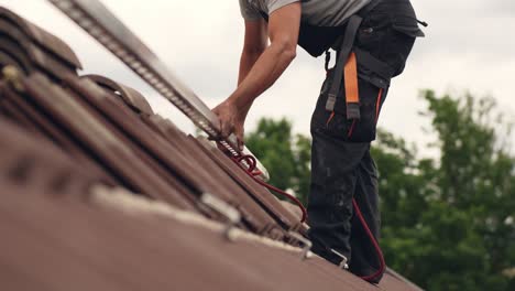 Ground-level-view-of-roofer-worker-adding-mounts-for-solar-panel-home,-day