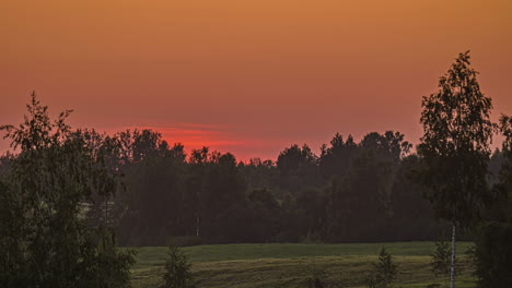 Ländliche-Landschaft-Mit-Dichten-Bäumen-Und-Grünen-Wiesen-Gegen-Feurigen-Sonnenunterganghimmel