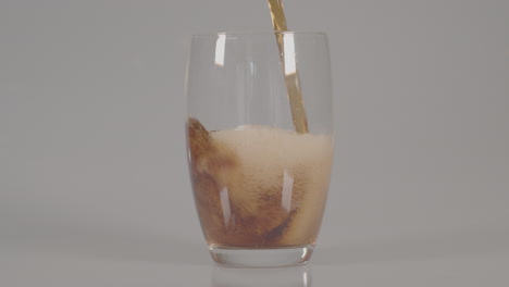 Cola-being-poured-into-glass-against-a-white-studio-background