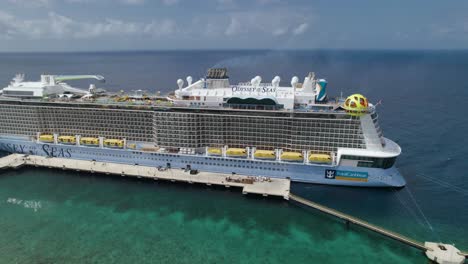 Aerial-orbit-over-the-Odyssey-of-the-Seas-cruise-ship-standing-on-the-pier-with-an-open-ocean-behind