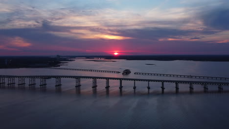 Drone-Shot-of-Beautiful-Pink-Sunset-Overlooking-Ocean-and-Bridge-in-Mississippi