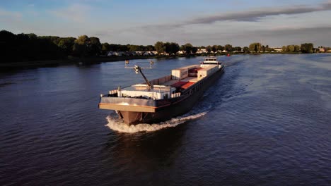 Aerial-Parallax-And-Tracking-Shot-Around-Forward-Bow-Of-FPS-Waal-Cargo-Container-Vessel-Travelling-On-Oude-Maas-During-Golden-Hour
