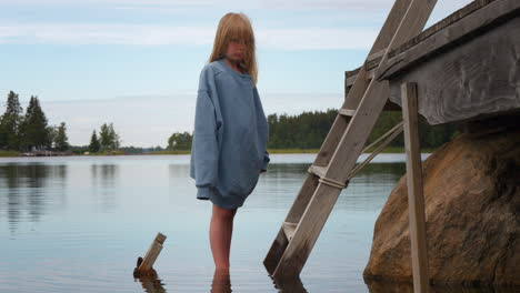 Portrait-of-sad-blonde-girl-standing-in-water-worried-about-rising-sea-levels