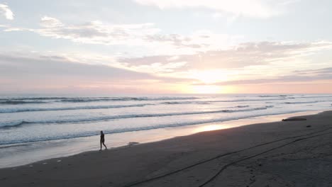 Woman-walking-along-playa-Bandera-during-a-beautiful-vibrant-sunset-in-Puntarenas,-Costa-Rica