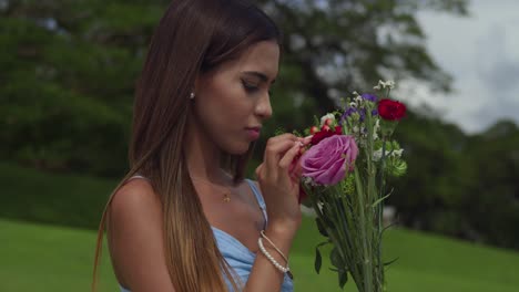 A-young-girl-smells-the-roses-and-flowers-facial-close-up-at-a-park