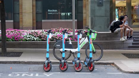 London-Canary-Wharf-Aug-2022-row-of-electric-scooters-and-bike-parked-by-the-side-of-the-road