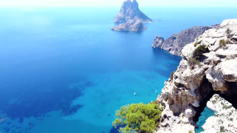 Flight-over-edge-of-cliff,-island-strong-sun-blue-water
Breathtaking-aerial-view-flight-tilt-up-drone-footage
of-cliff-edges-hike-Es-Vedra-Ibiza-summer-2022