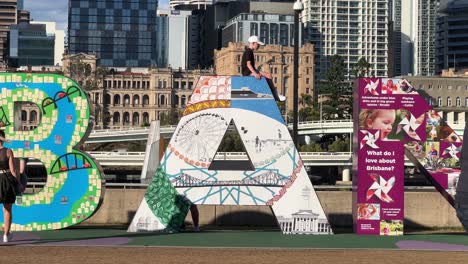 People-taking-photos-with-the-giant-colorful-block-letter-of-Brisbane,-the-iconic-landmark-at-downtown-river-bank-on-a-sunny-day,-Queensland-the-sunshine-state,-Australia,-close-up-shot
