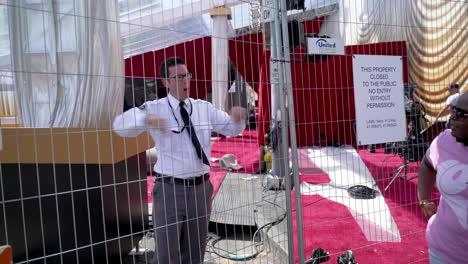 A-Security-Guard-Talks-to-Tourists-through-a-Fence-outside-the-Oscars-Red-Carpet