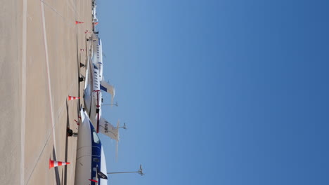 Vertical-Video-Private-Jets-Parked-at-Airport-Apron,-Sunny-Day